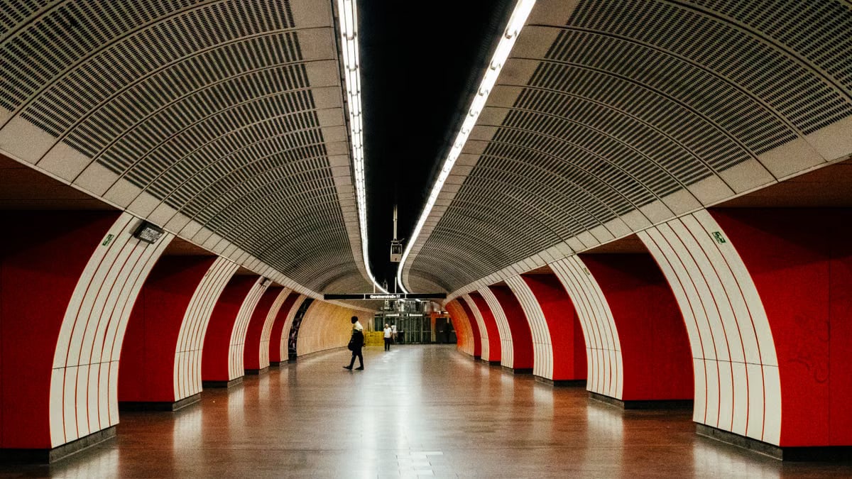 Symmetrical view of a modern subway station in Vienna with striking red arches.
